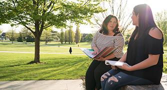 An image of two students working outside. 